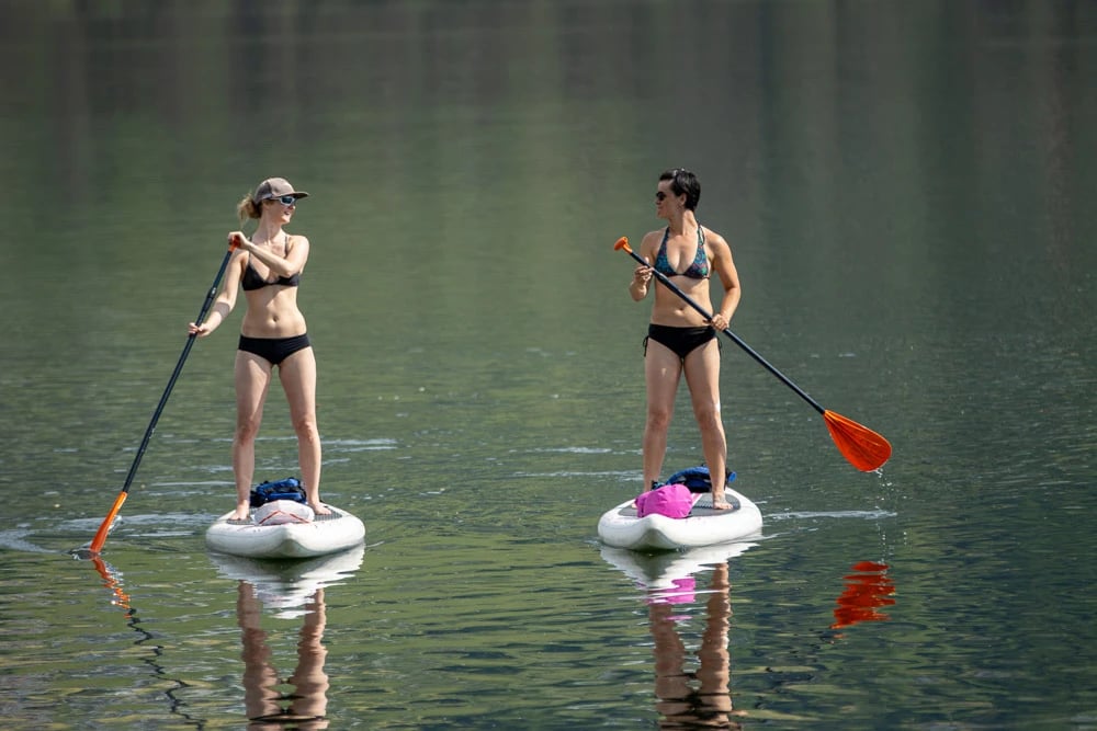Women paddleboarding on lake